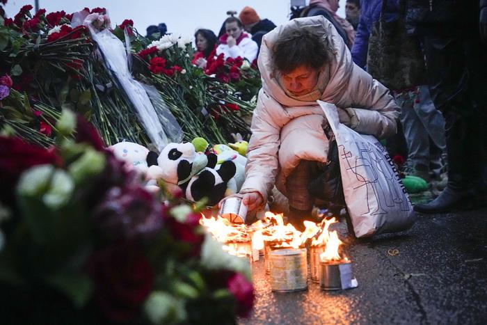 Persone che depongono fiori in memoria delle vittime dell'attacco compiuto a Mosca